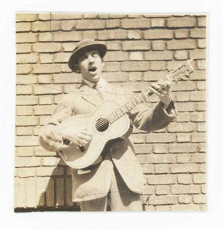 Item #29849 [Photograph of a Man With His Eyes Closed, Playing a Guitar in Front of a Brick...